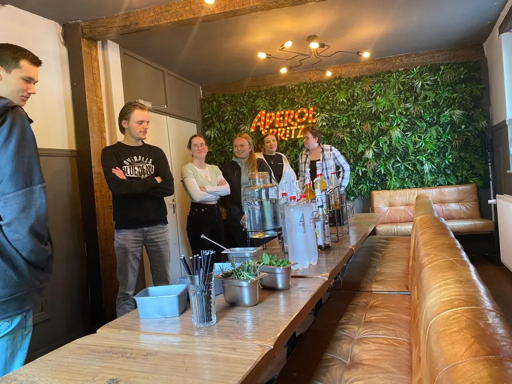 Workshop at the long table in front of the green plant wall with the Aperol neon sign at Restobar LURE