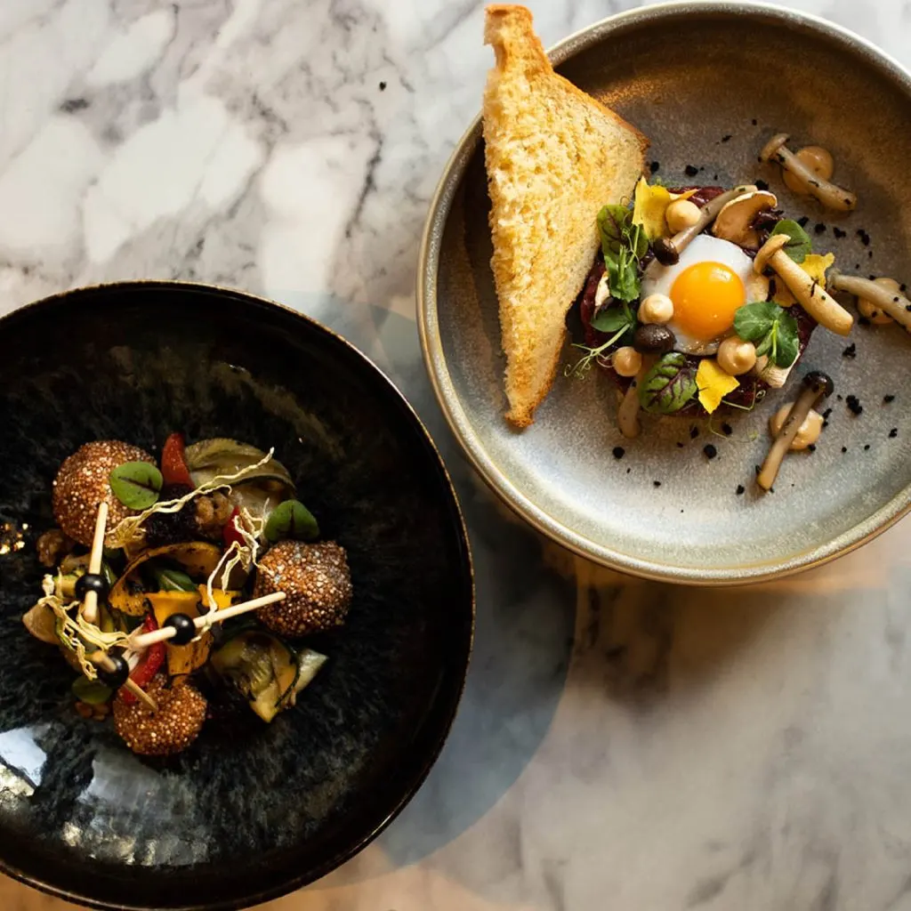 Twee diner-gerechten van Restobar LURE op een marmeren tafel